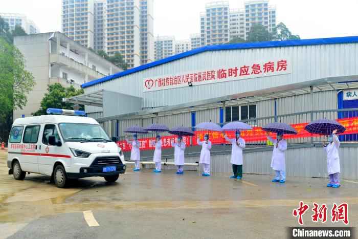 图为广西版“小汤山”医务人员送治愈患者离开。 李安祺 摄  广西版“小汤山”医院在院治疗近半数确诊患者治愈出院